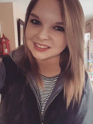 A young woman is taking a selfie in a living room.