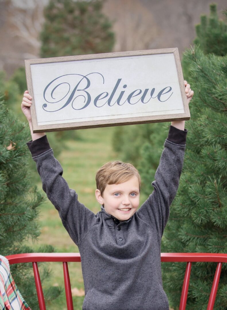 Two boys holding up a sign that says believe.