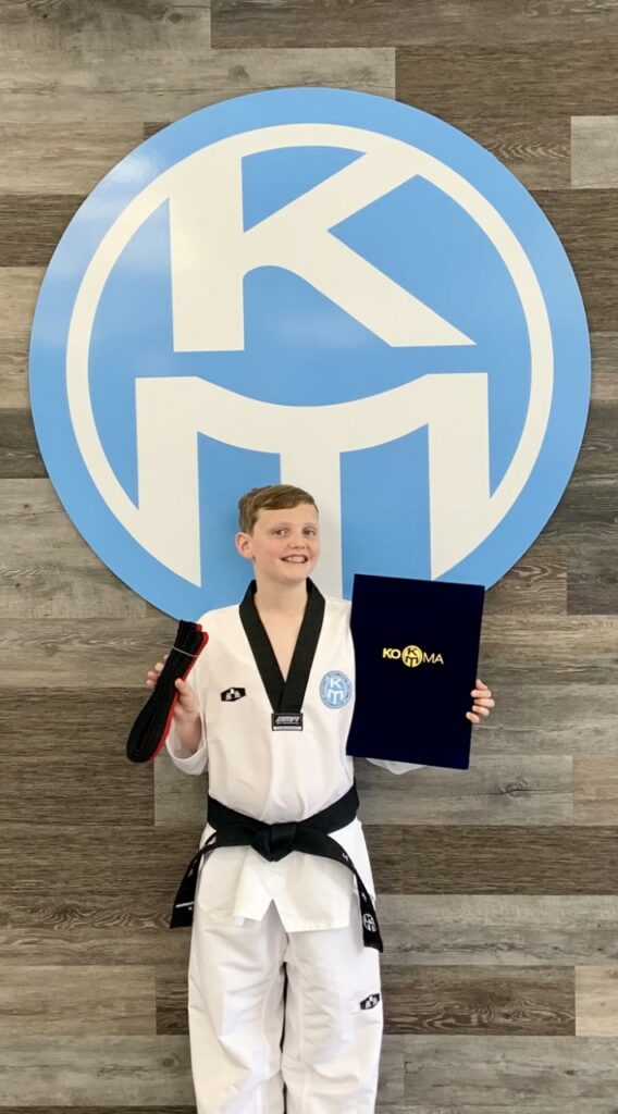 A boy in a karate uniform holding a certificate.