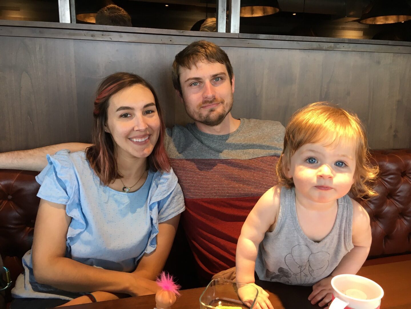 A man and woman sit at a table with a baby.