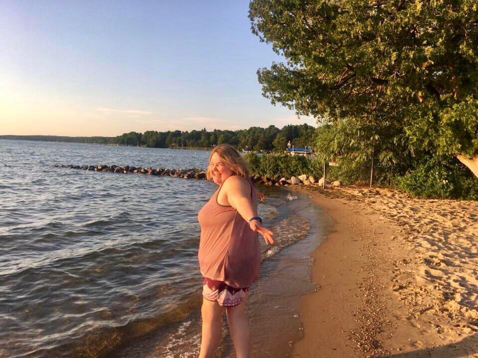 A woman standing on the shore of a lake.