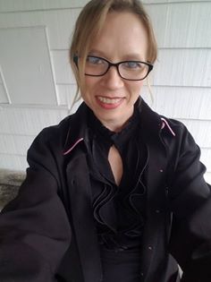 A woman wearing glasses and a black shirt is taking a selfie.