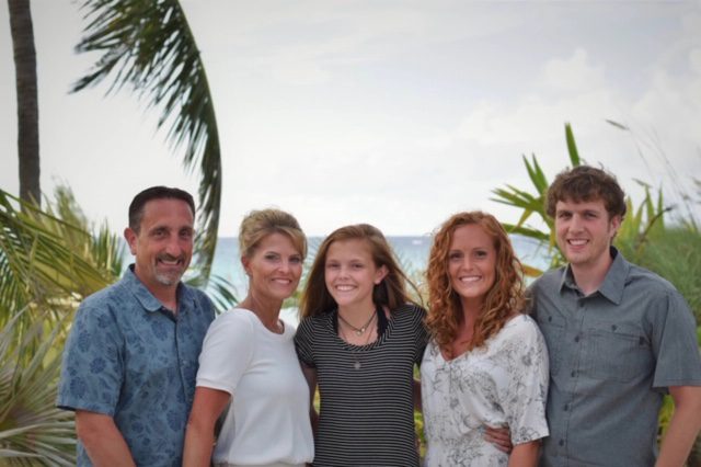 A family is posing for a picture in front of a palm tree.