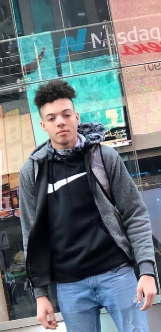 A young man standing in front of a building.