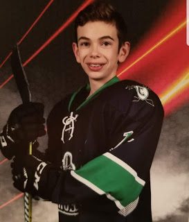 A young boy in a hockey uniform is posing for a photo.