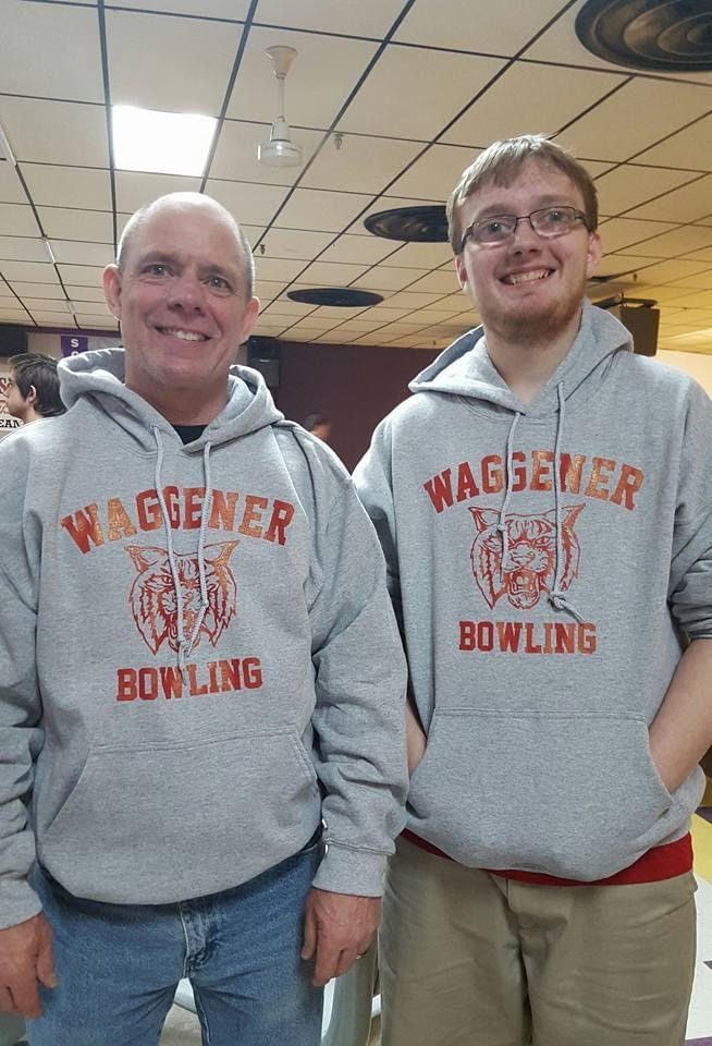 Two men posing for a photo in a bowling alley.