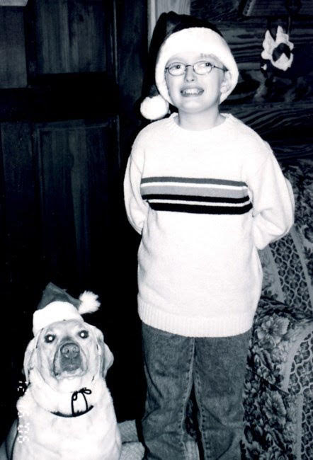 A boy in a santa hat and a dog in a santa hat.