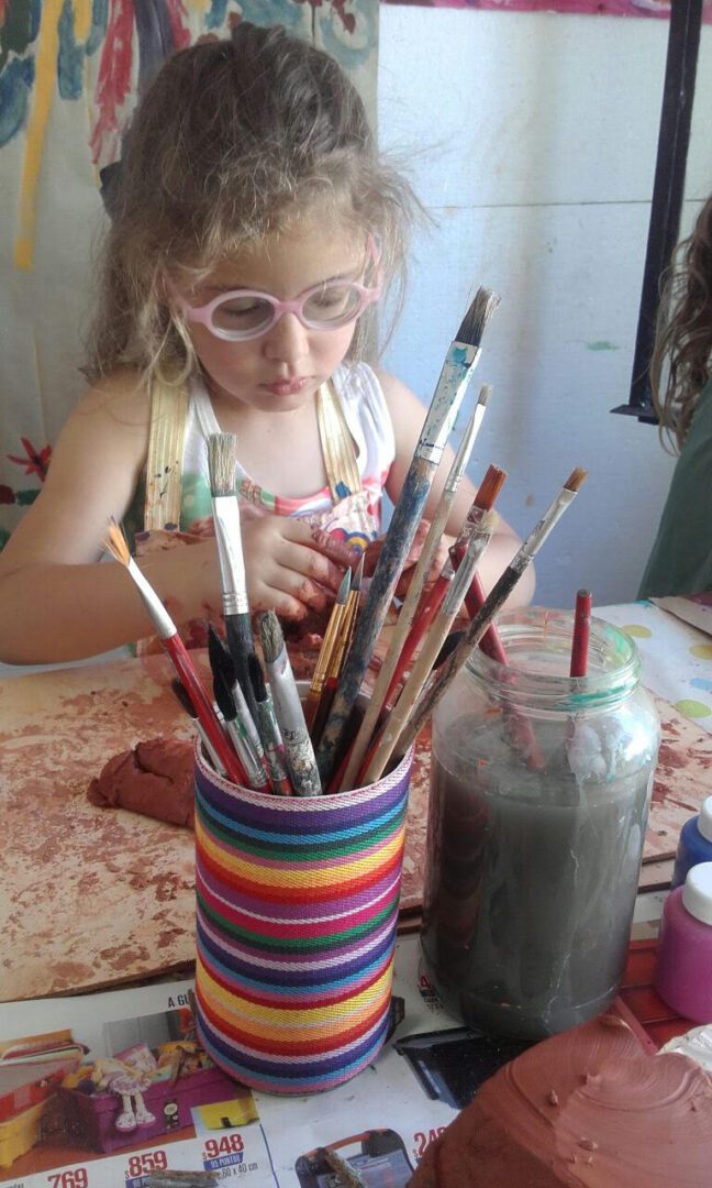 A little girl is working with clay at a table.