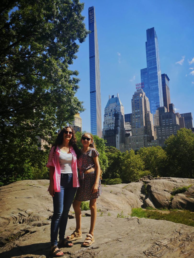 Two women posing in front of a city skyline.