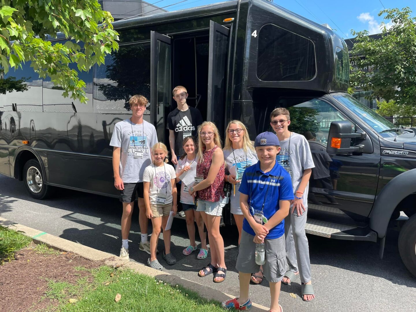 A group of people standing in front of a black bus.