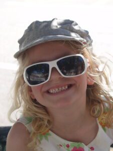 A little girl wearing a hat and sunglasses.