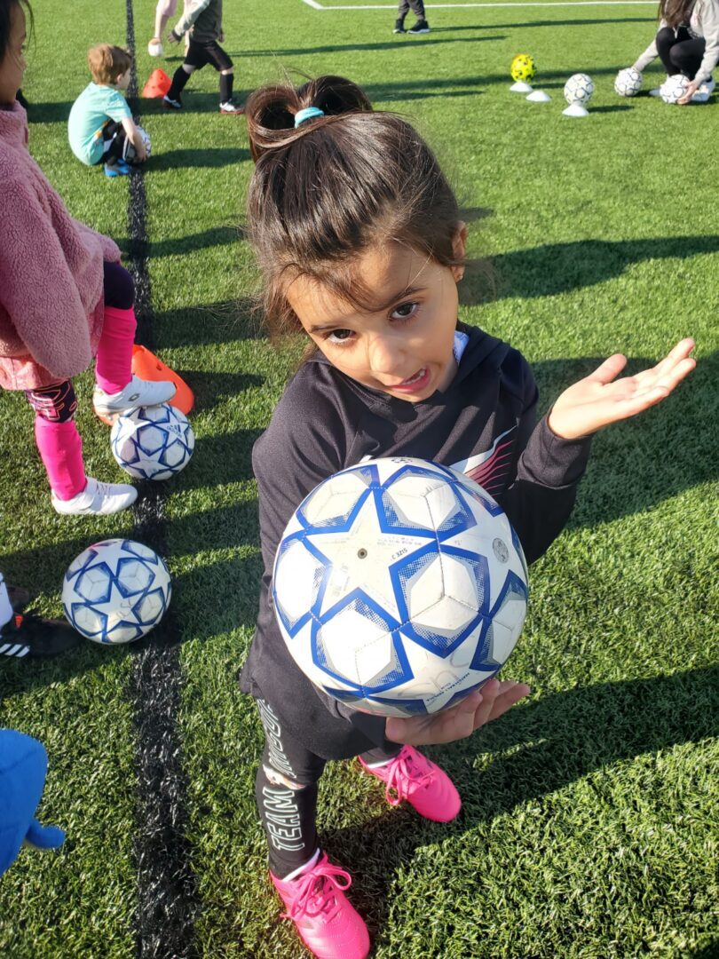 A young girl with a soccer ball participating in a game.