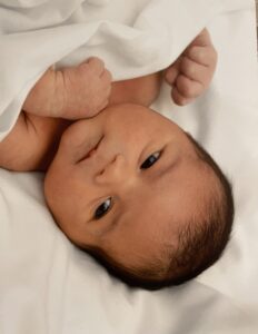 A newborn baby laying on a white blanket.