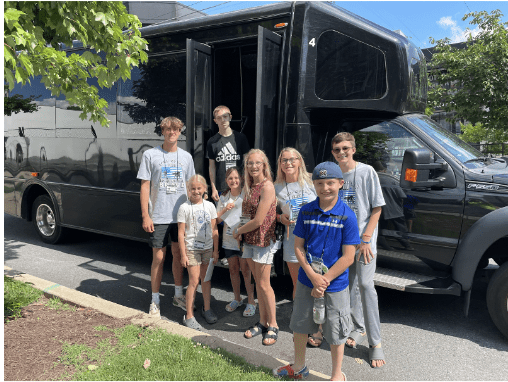 A group of people standing in front of a black bus.