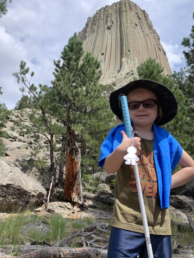 A young boy holding a pole in front of devils tower.