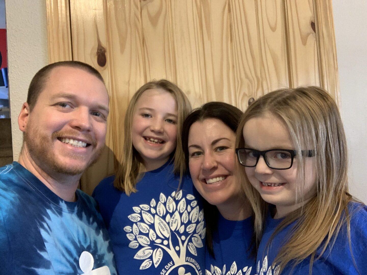 A family posing for a photo wearing blue t - shirts.