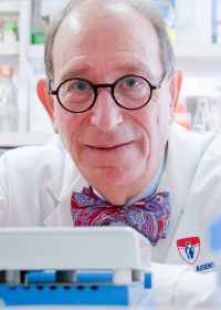 A man in a lab with glasses and a bow tie.