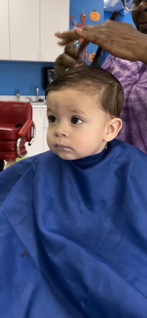 A woman cutting a child's hair in a salon.