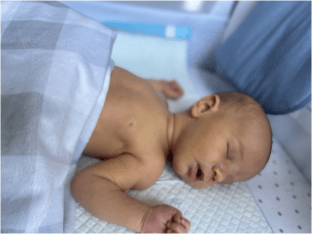 A baby is sleeping on a blue blanket in a crib.