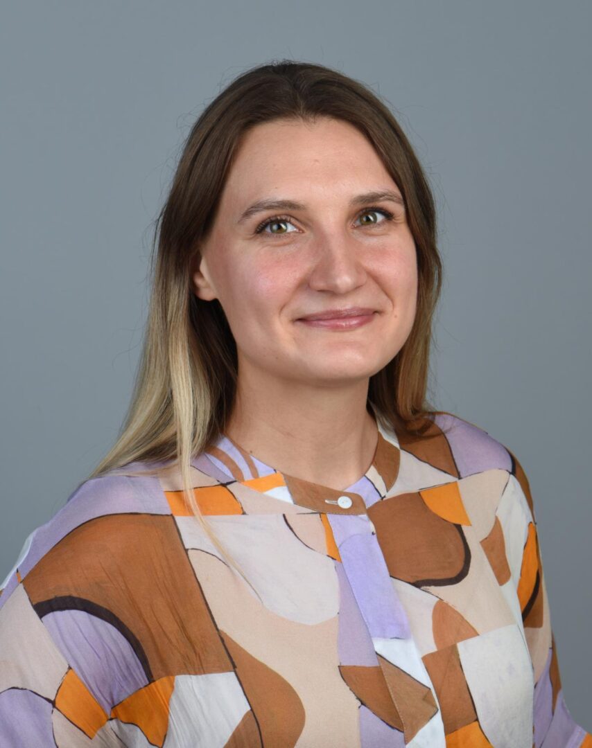 A woman in a colorful shirt is posing for a photo.