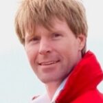 A man wearing a red jacket and white shirt.