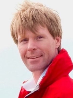 A man wearing a red jacket and white shirt.