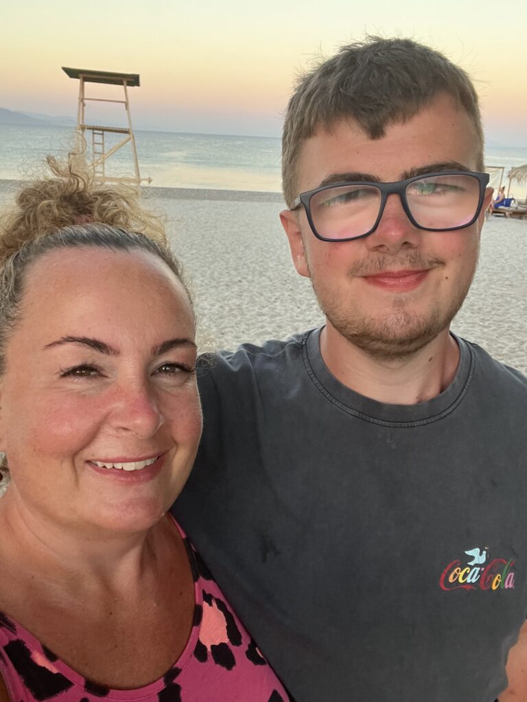 A mother and her son are smiling at the beach.