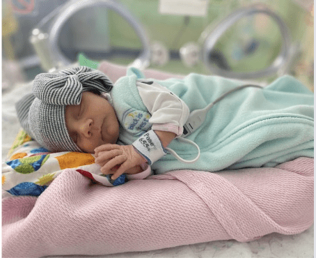 Sleeping newborn baby in a hospital crib.