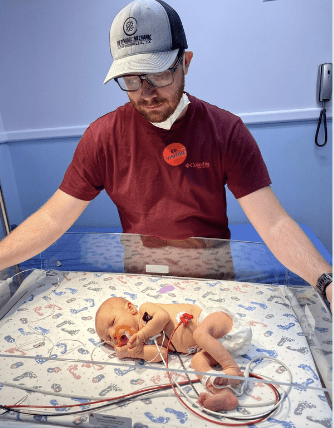 Man looking at a baby in an incubator.