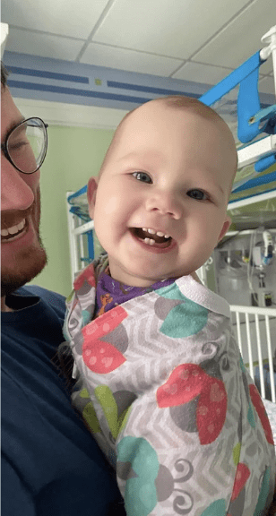 Smiling baby in a colorful onesie.