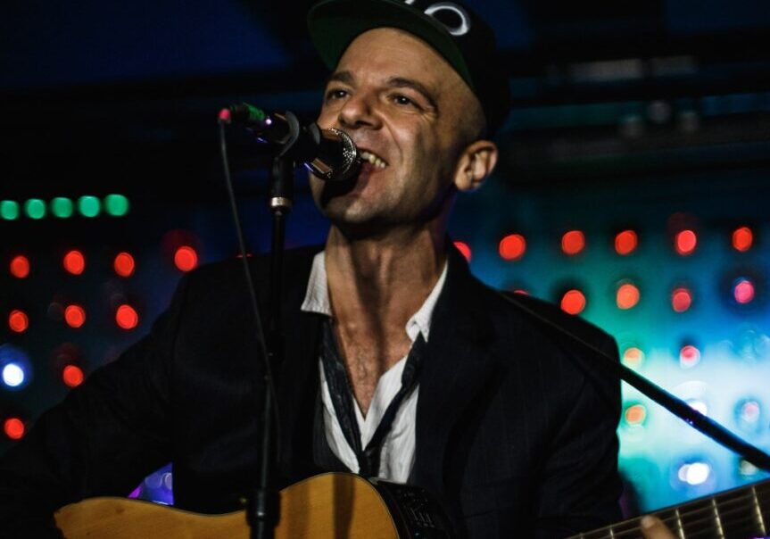 A Man Singing With Guitar on Stage