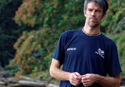 A man in a blue shirt standing next to a river.