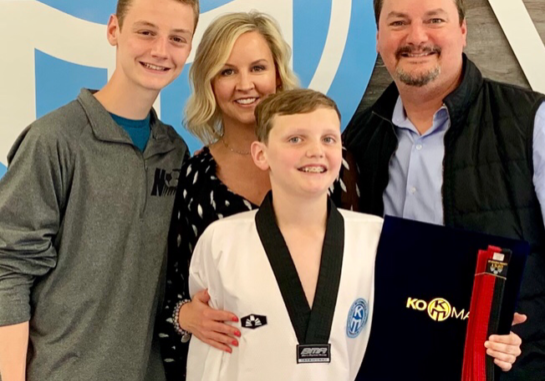 A family poses for a picture with a karate belt.