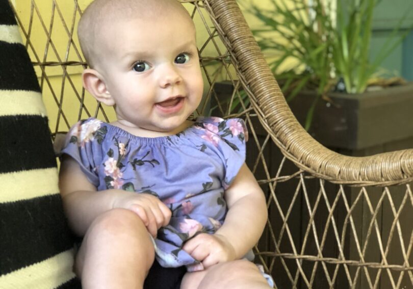 A baby sitting on a wicker chair.