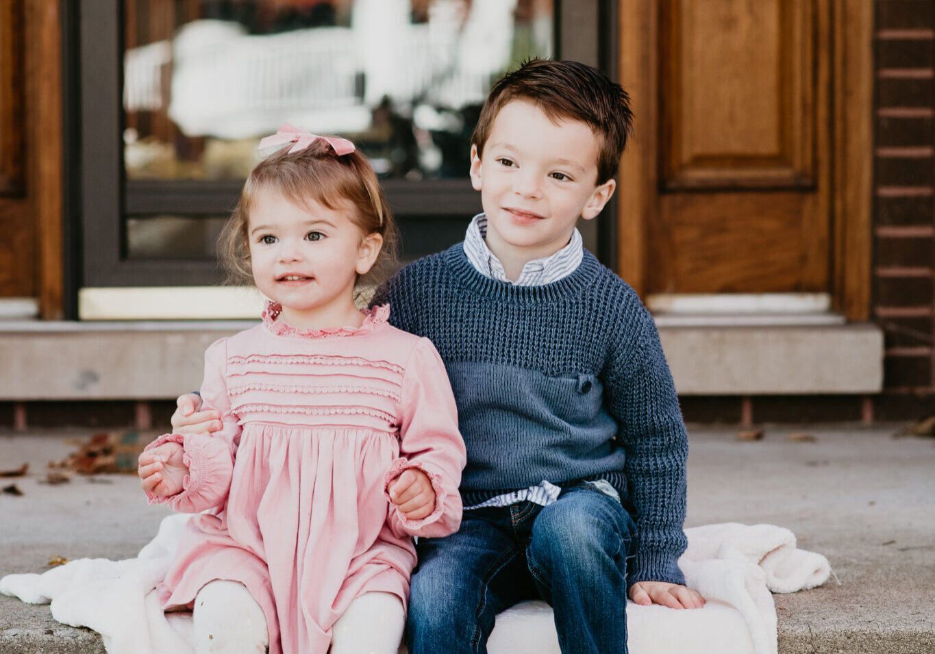 Two children sitting on steps in front of a house.