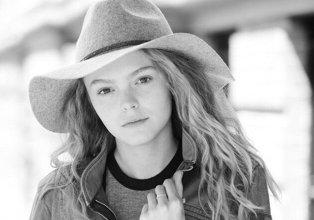 A black and white photo of a woman wearing a hat.