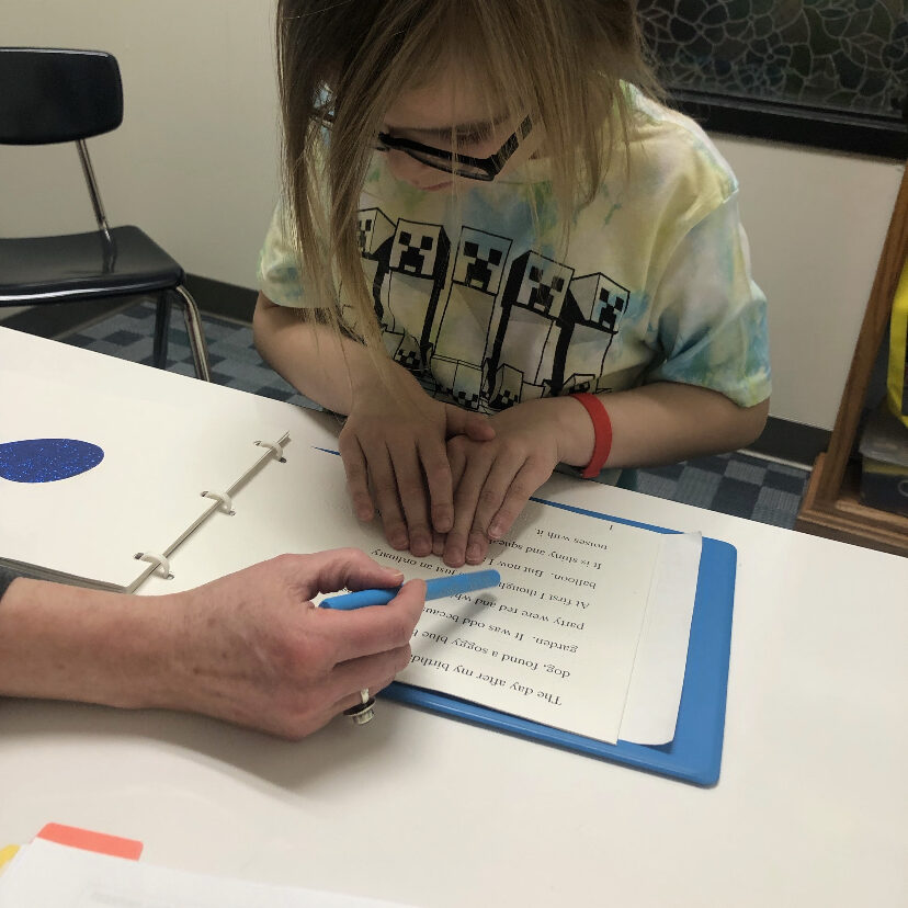 A young girl is writing on a piece of paper.