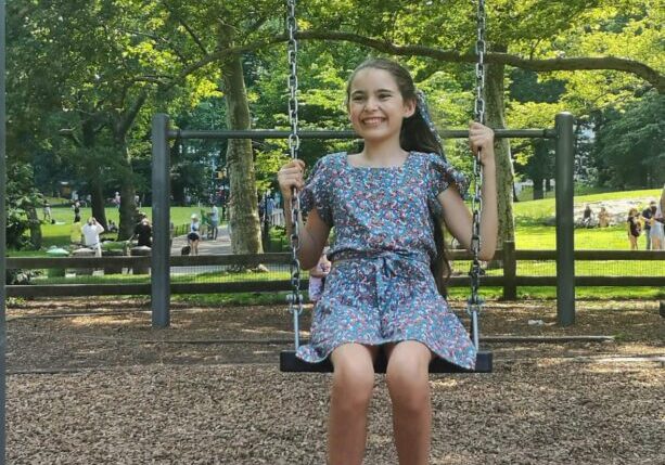 A girl is swinging on a swing in a park.