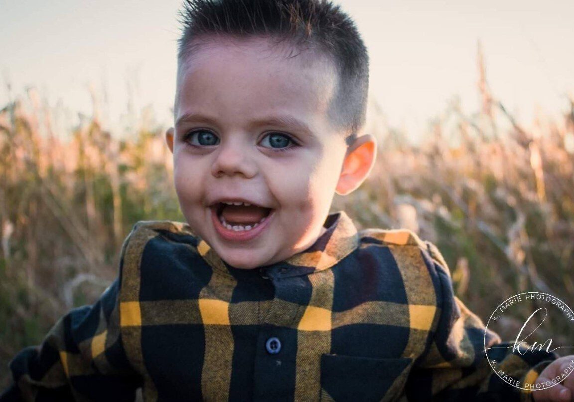 A young boy in a field with a smile on his face.