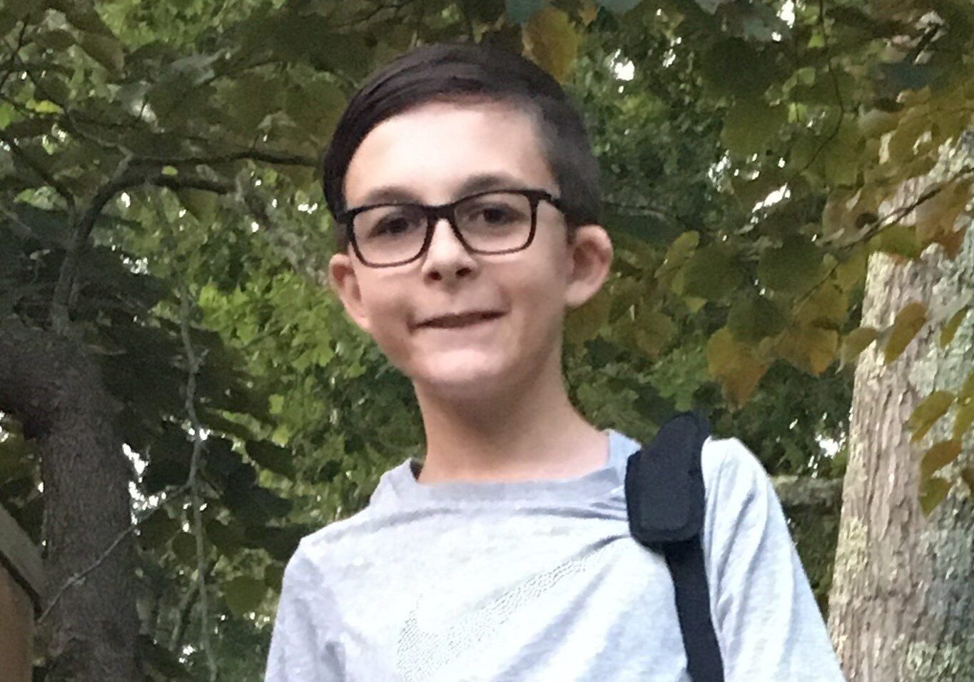 A young boy wearing glasses and a backpack.