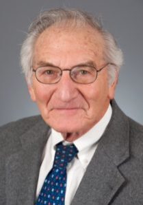 An older man wearing glasses and a blue tie.