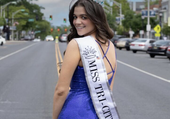 Smiling woman wearing a blue sequined gown and a tiara.