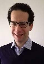 A man in glasses is smiling for the camera.