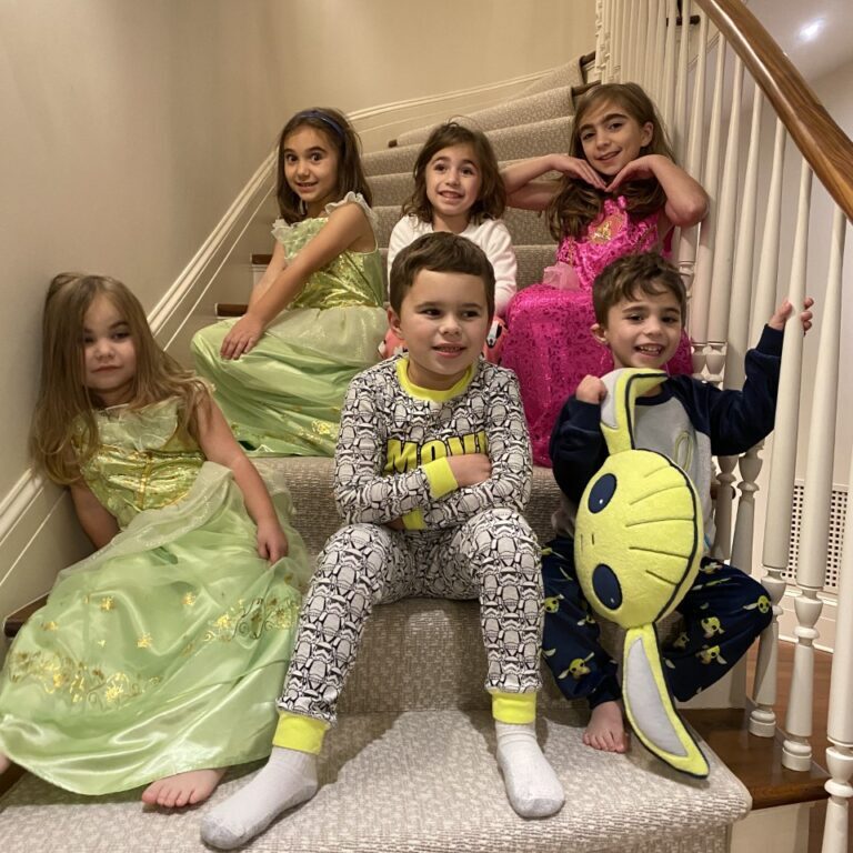 A group of children in pajamas posing on the stairs.