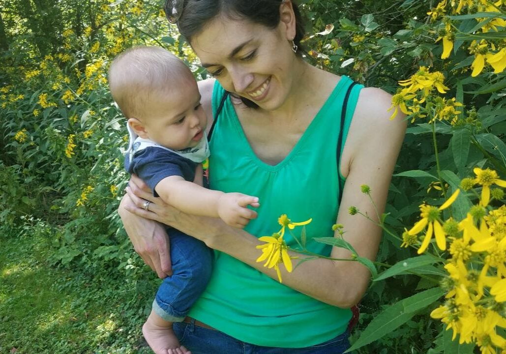 A woman holding a baby in a field of yellow flowers.