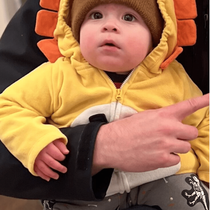 A man holding a baby in a lion costume.