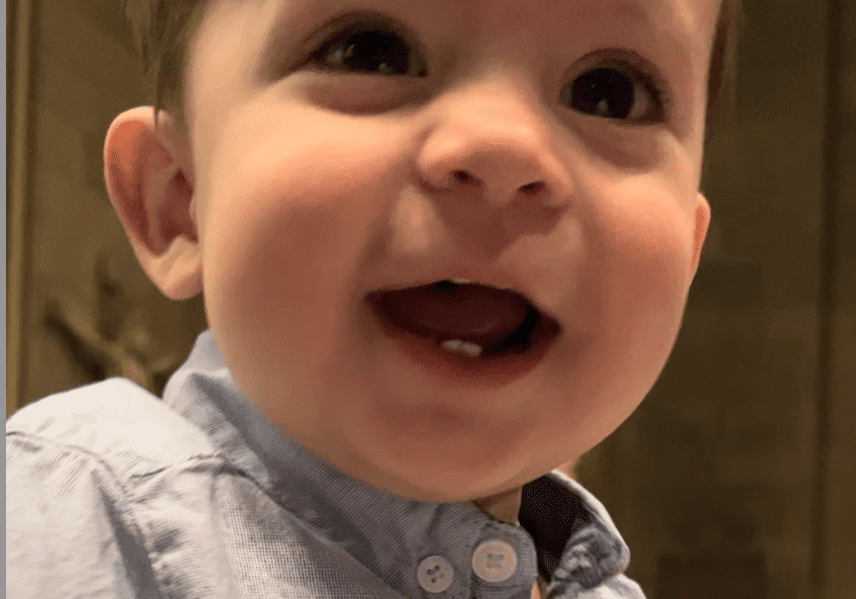 A baby is smiling with his mouth open.