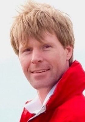 A man wearing a red jacket and white shirt.