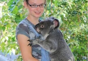 A girl is holding a koala at the zoo.