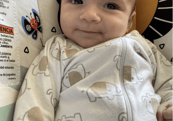 Smiling baby wearing an elephant onesie.